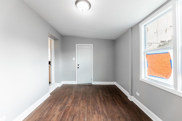 empty room with dark wood-type flooring and lofted ceiling