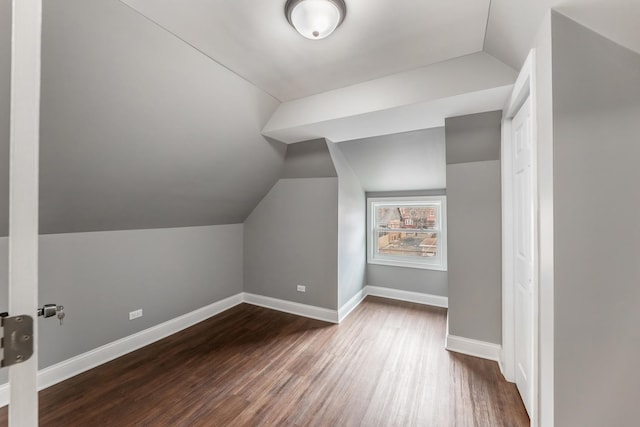 additional living space featuring dark wood-type flooring and lofted ceiling