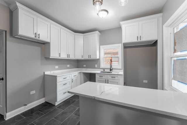 kitchen featuring kitchen peninsula, white cabinetry, and sink