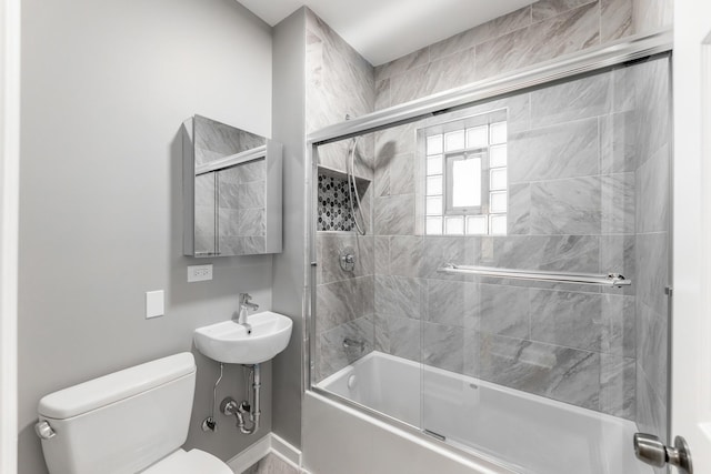 bathroom with toilet and bath / shower combo with glass door