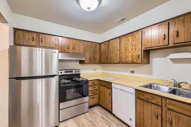 kitchen with sink, appliances with stainless steel finishes, and light hardwood / wood-style flooring