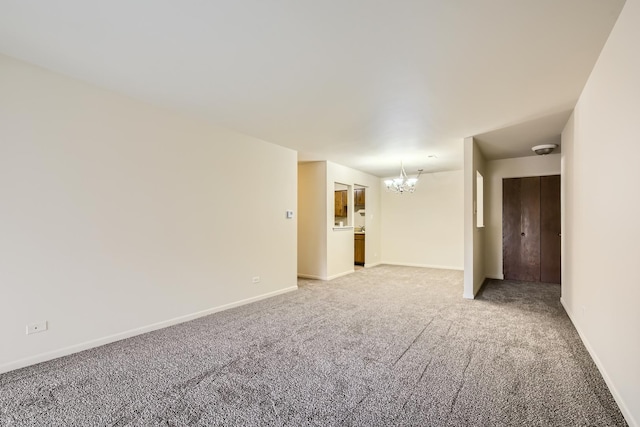 carpeted spare room with an inviting chandelier