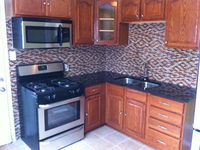 kitchen featuring decorative backsplash, appliances with stainless steel finishes, light tile patterned floors, and sink