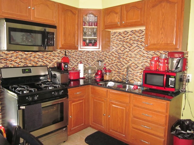 kitchen featuring backsplash, sink, dark stone counters, and stainless steel appliances