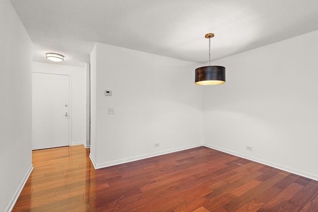 unfurnished dining area with a textured ceiling and dark hardwood / wood-style floors