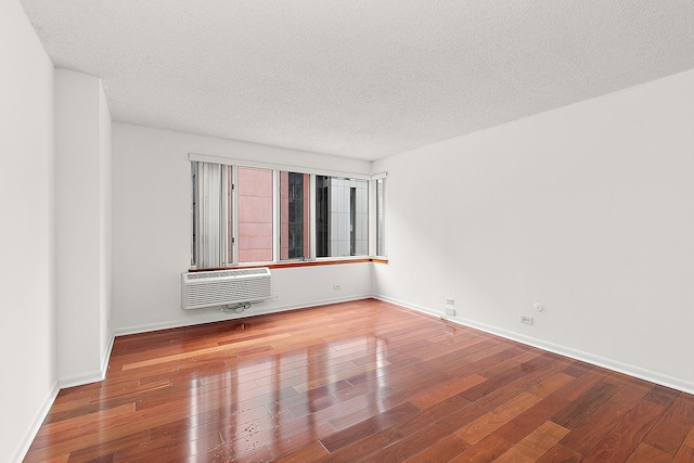 unfurnished room featuring a wall mounted AC, a textured ceiling, and hardwood / wood-style flooring