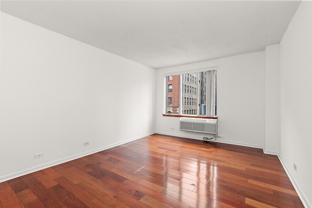 unfurnished room with wood-type flooring, a textured ceiling, and a wall mounted AC