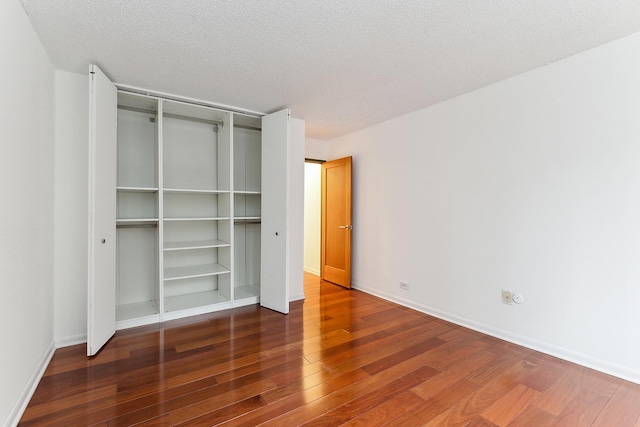 unfurnished bedroom with a textured ceiling and dark hardwood / wood-style floors