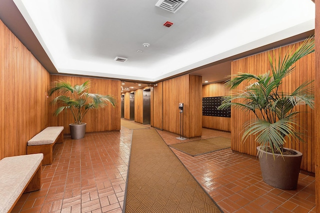 hall with a tray ceiling and wooden walls