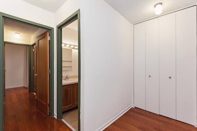 corridor featuring dark hardwood / wood-style flooring, a textured ceiling, and sink