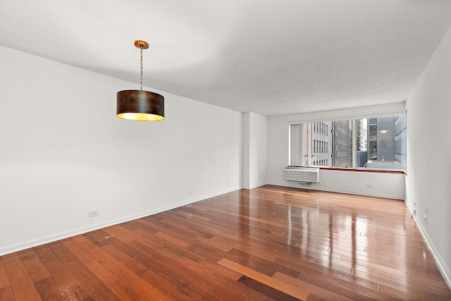 unfurnished living room featuring wood-type flooring, a textured ceiling, and an AC wall unit