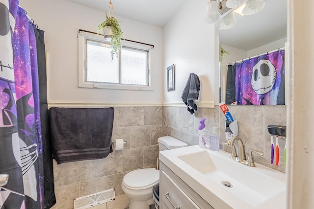 bathroom featuring vanity, tile walls, and toilet