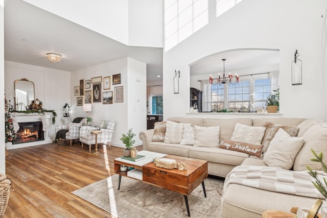 living room with a chandelier, wood-type flooring, and a high ceiling