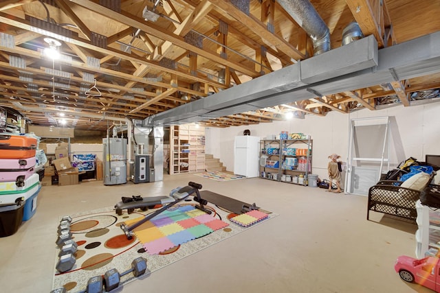 basement with white refrigerator, gas water heater, and heating unit