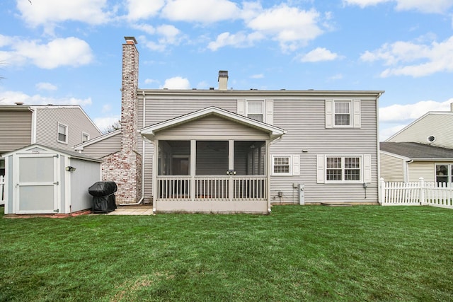 back of house with a yard, a storage unit, and a sunroom