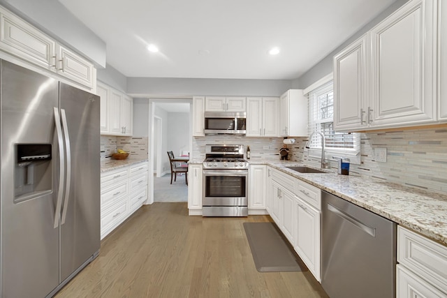 kitchen with tasteful backsplash, white cabinetry, sink, and appliances with stainless steel finishes