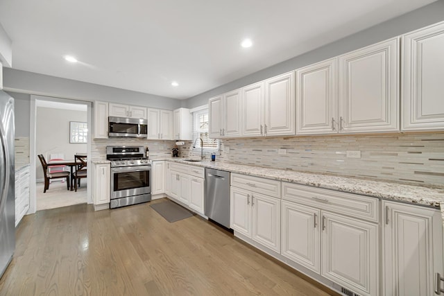 kitchen featuring light hardwood / wood-style floors, sink, appliances with stainless steel finishes, and tasteful backsplash