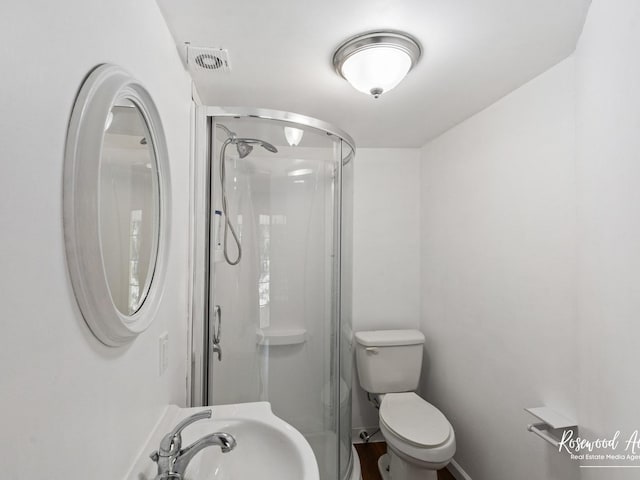 bathroom featuring toilet, an enclosed shower, and sink