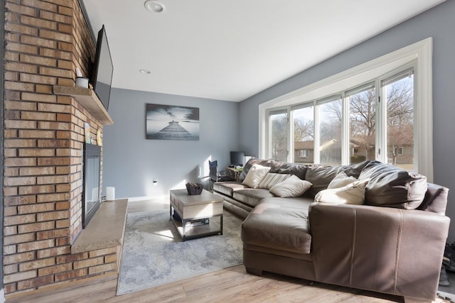 living room featuring light hardwood / wood-style floors and a brick fireplace