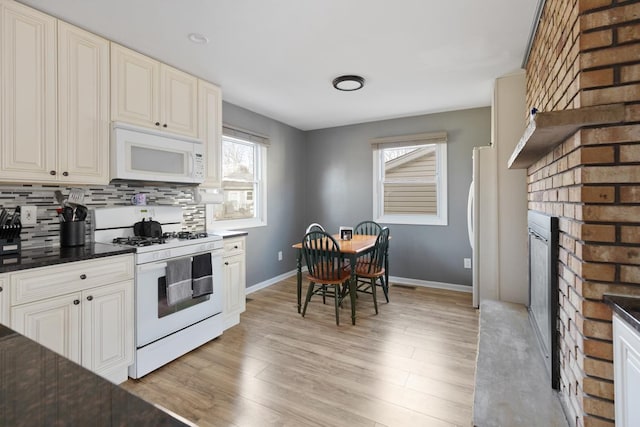 kitchen featuring a brick fireplace, white appliances, light hardwood / wood-style flooring, and tasteful backsplash