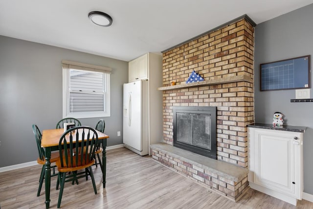 dining area featuring light wood-type flooring and a fireplace