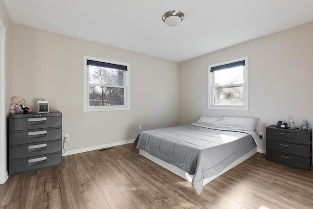 bedroom with dark hardwood / wood-style floors and multiple windows