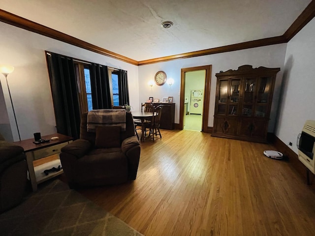 living room with hardwood / wood-style flooring, ornamental molding, and heating unit