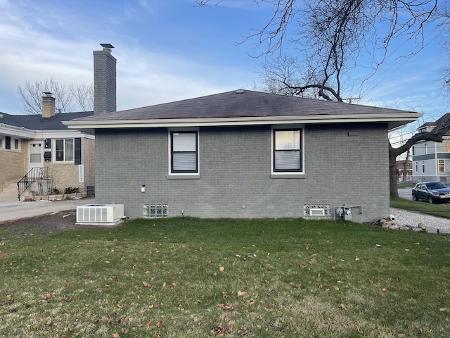 back of property featuring a lawn and cooling unit