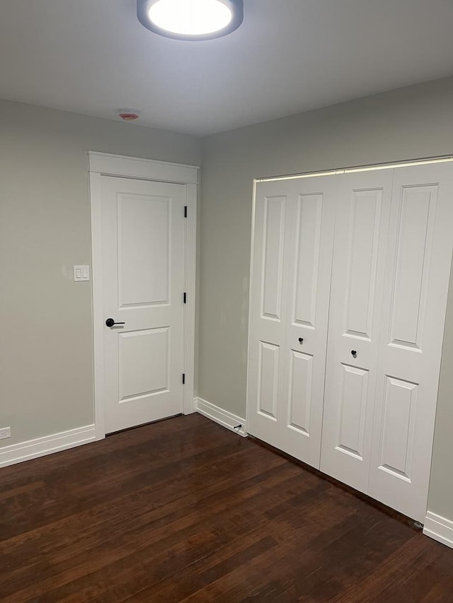 unfurnished bedroom featuring a closet and dark hardwood / wood-style flooring