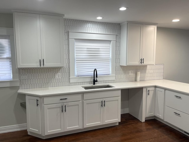 kitchen with backsplash, dark hardwood / wood-style floors, white cabinetry, and sink