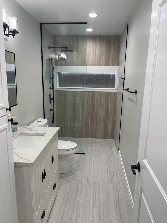 bathroom featuring toilet, a tile shower, and vanity