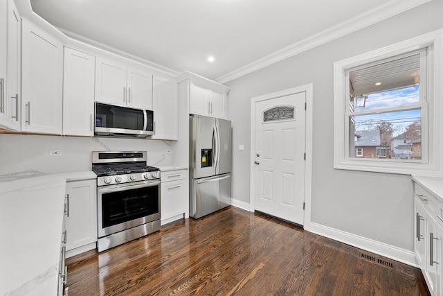 kitchen with appliances with stainless steel finishes, dark hardwood / wood-style flooring, light stone counters, ornamental molding, and white cabinets