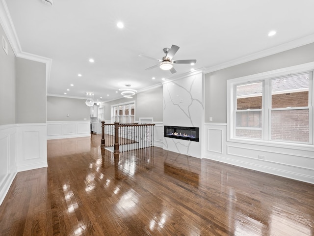 unfurnished living room with a large fireplace, dark wood-type flooring, ceiling fan, and ornamental molding