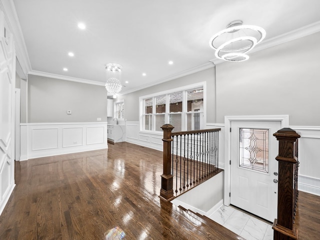 foyer entrance with crown molding, a chandelier, and hardwood / wood-style flooring