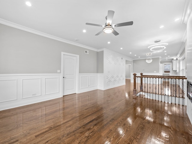 spare room featuring hardwood / wood-style floors, ceiling fan with notable chandelier, and ornamental molding