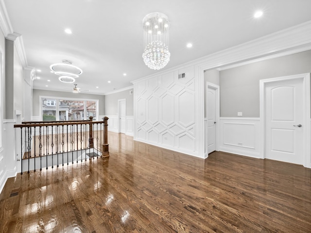 spare room with ceiling fan with notable chandelier, crown molding, and dark wood-type flooring