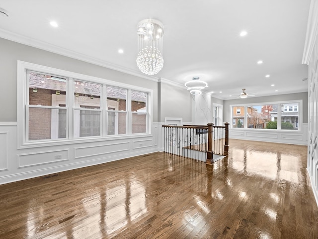 unfurnished room with wood-type flooring, ceiling fan with notable chandelier, and ornamental molding