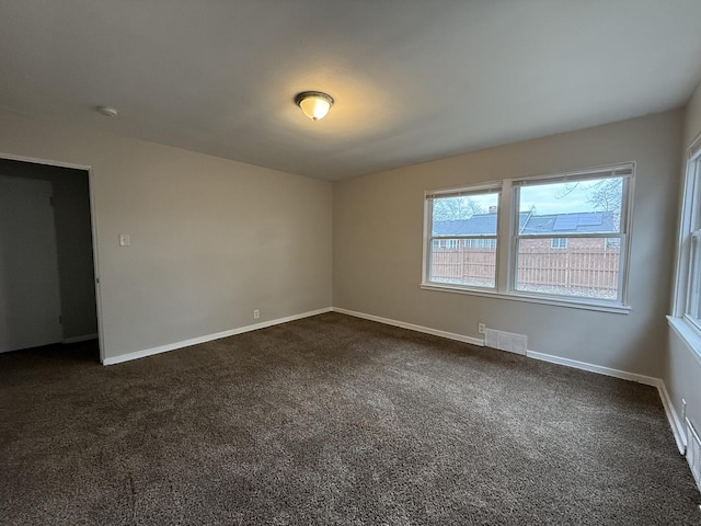 unfurnished room featuring dark colored carpet