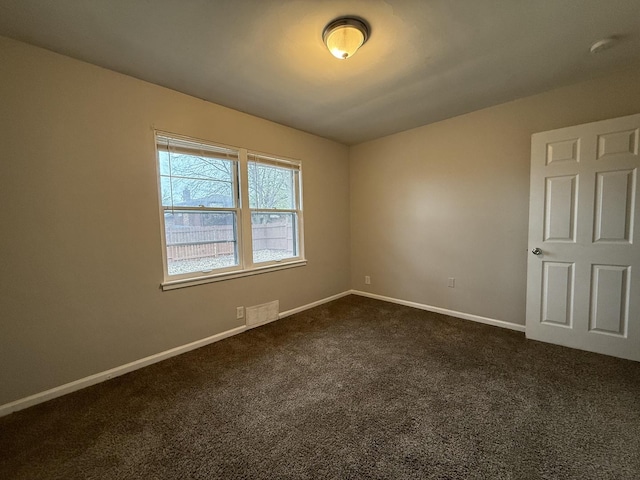 spare room featuring dark colored carpet