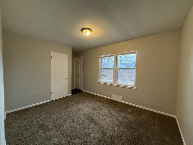 unfurnished room featuring dark colored carpet