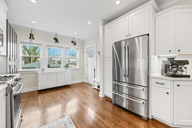 kitchen with dark wood-type flooring, white cabinets, appliances with stainless steel finishes, and ornamental molding