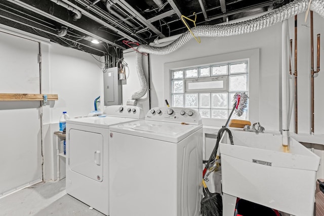 washroom with electric panel, washing machine and clothes dryer, and sink