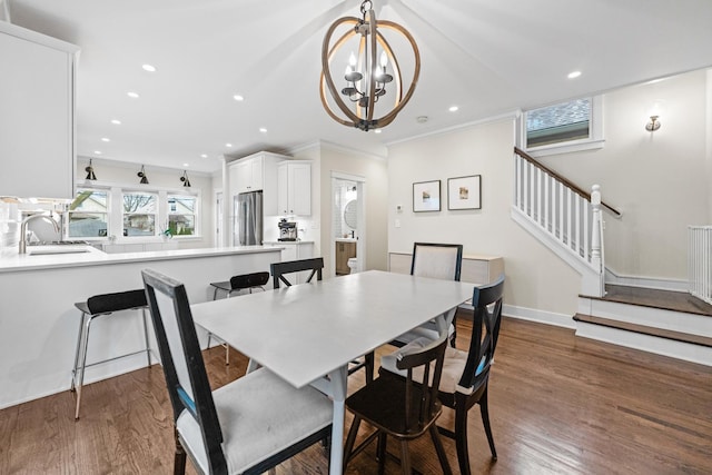 dining space with dark wood-type flooring, sink, crown molding, and a notable chandelier