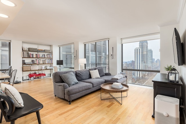 living room featuring floor to ceiling windows, crown molding, and light wood-type flooring