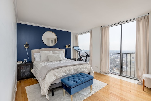 bedroom with wood-type flooring, expansive windows, and crown molding