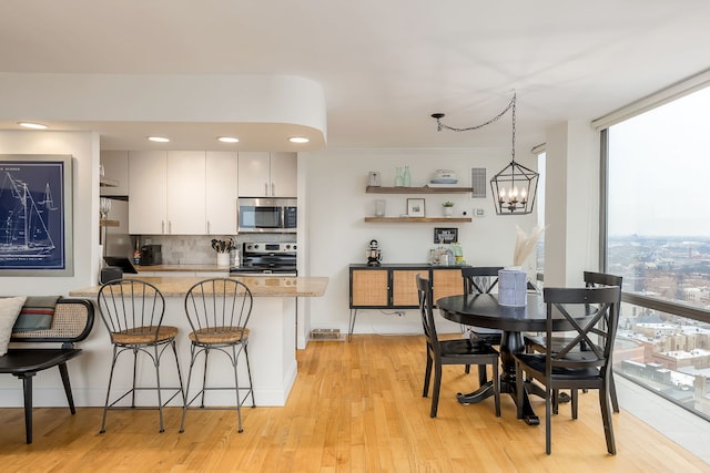 kitchen with backsplash, a notable chandelier, white cabinets, range, and hanging light fixtures