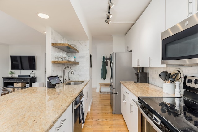 kitchen featuring track lighting, sink, light stone countertops, white cabinetry, and stainless steel appliances