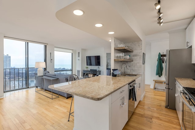 kitchen featuring a kitchen breakfast bar, appliances with stainless steel finishes, sink, light hardwood / wood-style flooring, and white cabinets