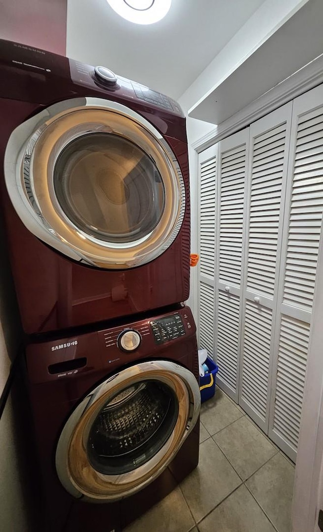 washroom featuring stacked washing maching and dryer and light tile patterned flooring