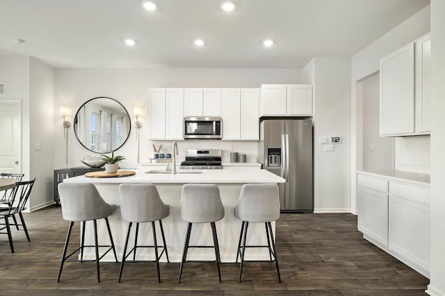 kitchen with white cabinetry, stainless steel appliances, and a center island with sink